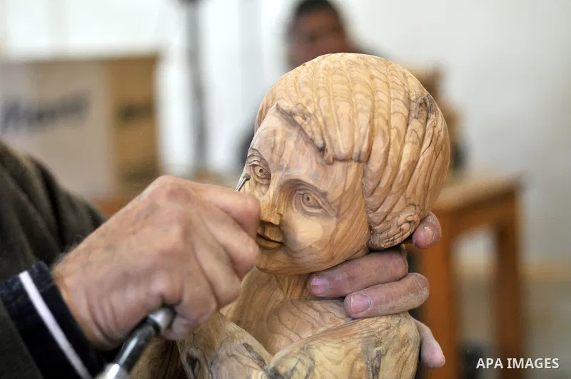 A Palestinian carpenter carves a wooden sculpture of baby Jesus at a workshop in the West Bank town of Bethlehem, on December 20, 2012. The traditional birthplace of Jesus Christ prepares to celebrate Christmas later thi...