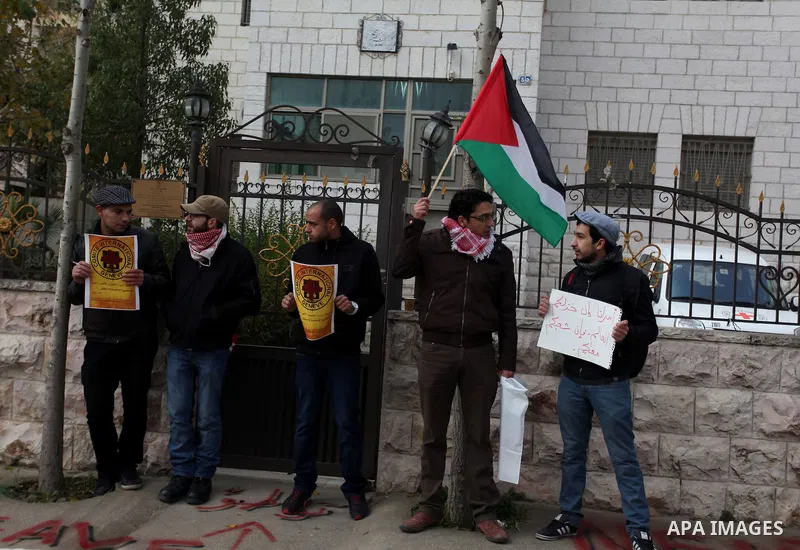 Palestinian protesters hold posters and a sign reading "ICRC, do your work or leave" during a demonstration in support of Palestinian prisoners held in Israeli jails, some of whom are observing a hunger strike, outside t...