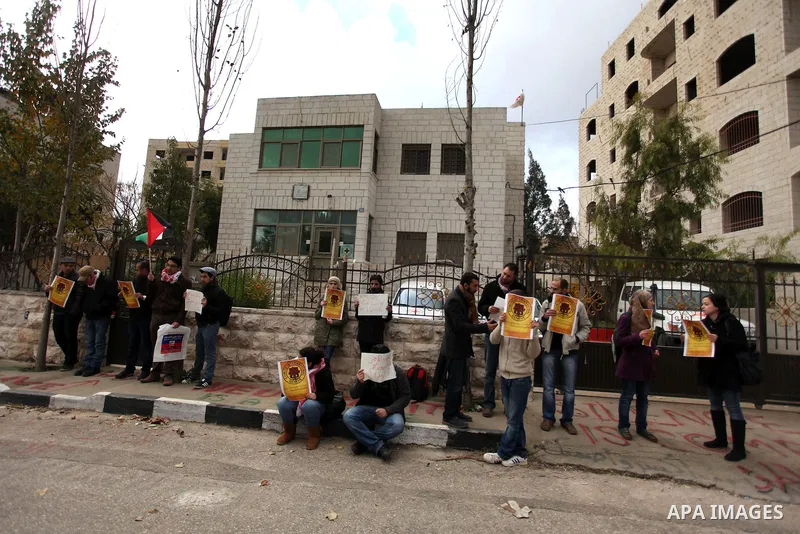 Palestinian protesters hold posters and a sign reading "ICRC, do your work or leave" during a demonstration in support of Palestinian prisoners held in Israeli jails, some of whom are observing a hunger strike, outside t...