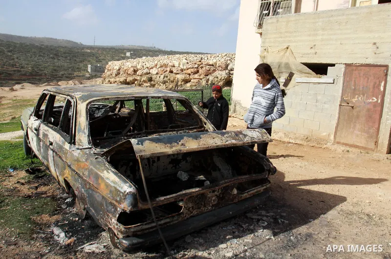 Palestinian children inspect wreckage of a car in the village of Majdal Bani Fadel, near the West Bank City of Nablus, 20 December 2012. According to Palestinian security officials two cars were set on fire in a raid by...
