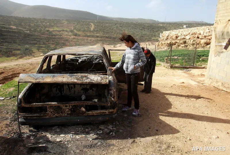 Palestinian children inspect wreckage of a car in the village of Majdal Bani Fadel, near the West Bank City of Nablus, 20 December 2012. According to Palestinian security officials two cars were set on fire in a raid by...
