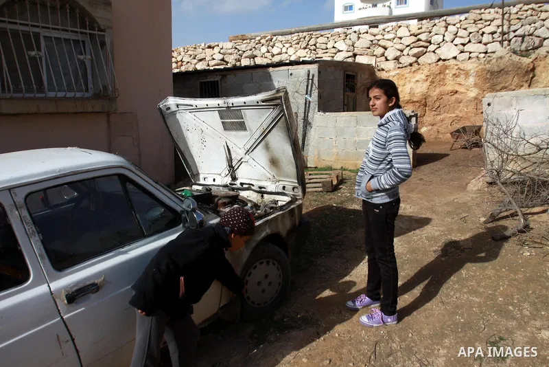 Palestinian children inspect wreckage of a car in the village of Majdal Bani Fadel, near the West Bank City of Nablus, 20 December 2012. According to Palestinian security officials two cars were set on fire in a raid by...