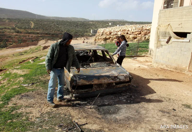 A Palestinian man inspects the wreckage of his car in the village of Majdal Bani Fadel, near the West Bank City of Nablus, 20 December 2012. According to Palestinian security officials two cars were set on fire in a raid...