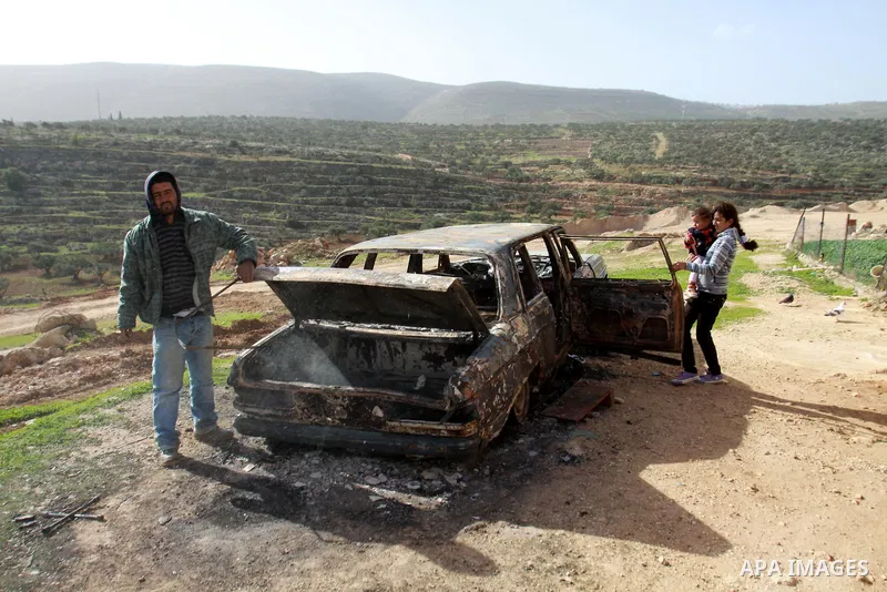 A Palestinian man inspects the wreckage of his car in the village of Majdal Bani Fadel, near the West Bank City of Nablus, 20 December 2012. According to Palestinian security officials two cars were set on fire in a raid...