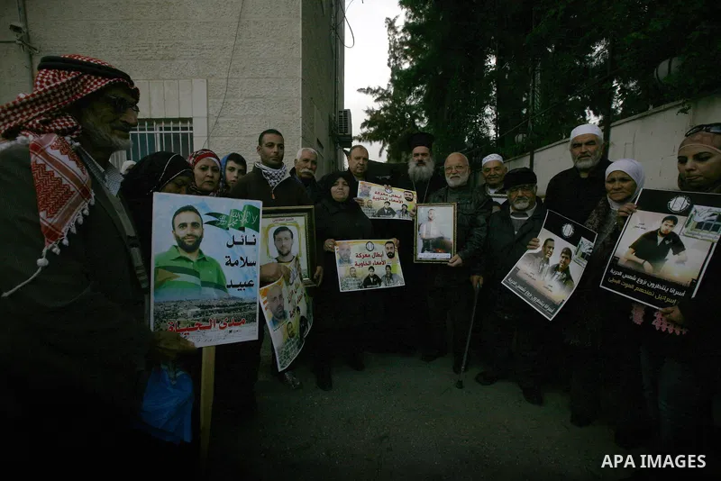 Palestinians hold pictures of prisoners held in Israeli jails during a sit-in outside the Red Cross offices in Jerusalem on December 20, 2012. in solidarity with hunger-striking detainees held by Israel to demand their r...