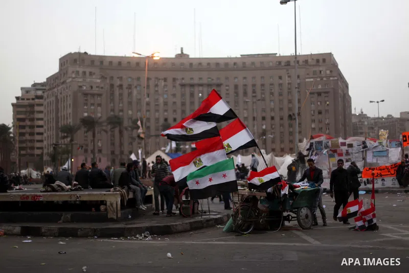 People walk past a stall displaying Egyptian flags for sale at Tahrir Square where protesters opposing President Mohamed Mursi are camping in Cairo December 20, 2012. Egyptian Islamist groups are planning a mass protest...