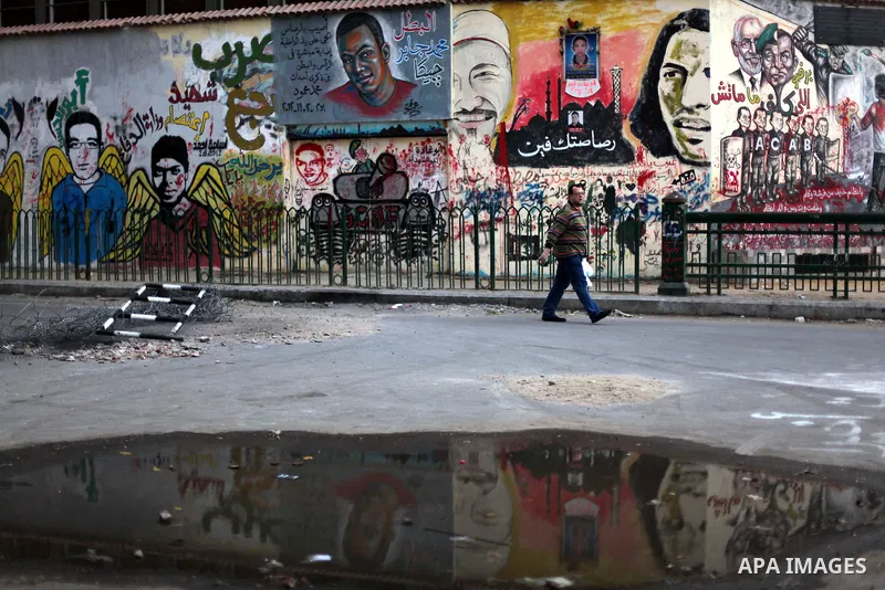 People walk past a wall graffiti at Tahrir Square where protesters opposing President Mohamed Mursi are camping in Cairo December 20, 2012. Egyptian Islamist groups are planning a mass protest in Alexandria on Friday, a...