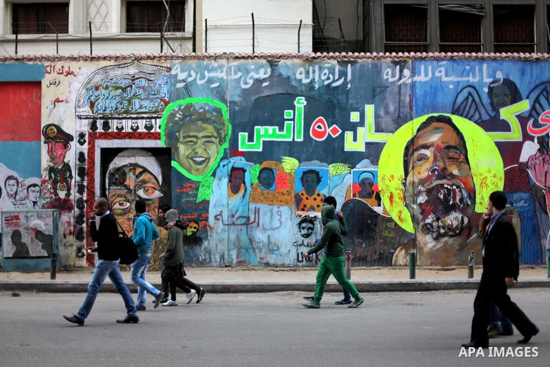 People walk past a wall graffiti at Tahrir Square where protesters opposing President Mohamed Mursi are camping in Cairo December 20, 2012. Egyptian Islamist groups are planning a mass protest in Alexandria on Friday, a...