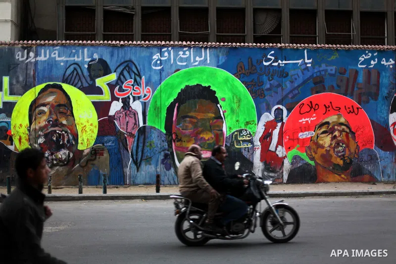 People walk past a wall graffiti at Tahrir Square where protesters opposing President Mohamed Mursi are camping in Cairo December 20, 2012. Egyptian Islamist groups are planning a mass protest in Alexandria on Friday, a...