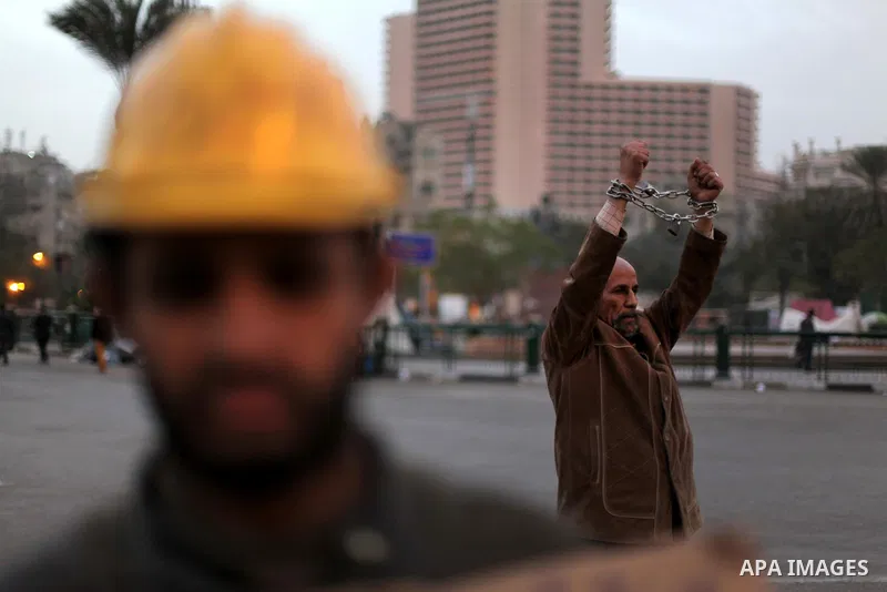 An Egyptian protester with chains around his wrists stands at Tahrir Square where protesters opposing President Mohamed Mursi are camping in Cairo December 20, 2012. Egyptian Islamist groups are planning a mass protest i...