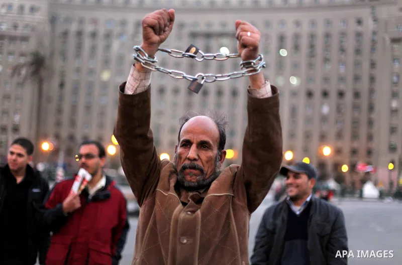 An Egyptian protester with chains around his wrists stands at Tahrir Square where protesters opposing President Mohamed Mursi are camping in Cairo December 20, 2012. Egyptian Islamist groups are planning a mass protest i...