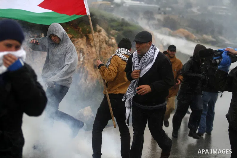 Palestinian protesters run cover from tear gas fired by Israeli soliers, during clashes with stone-throwing protesters in the West Bank village of Nabi Saleh, near Ramallah December 21, 2012. Photo by Issam Rimawi