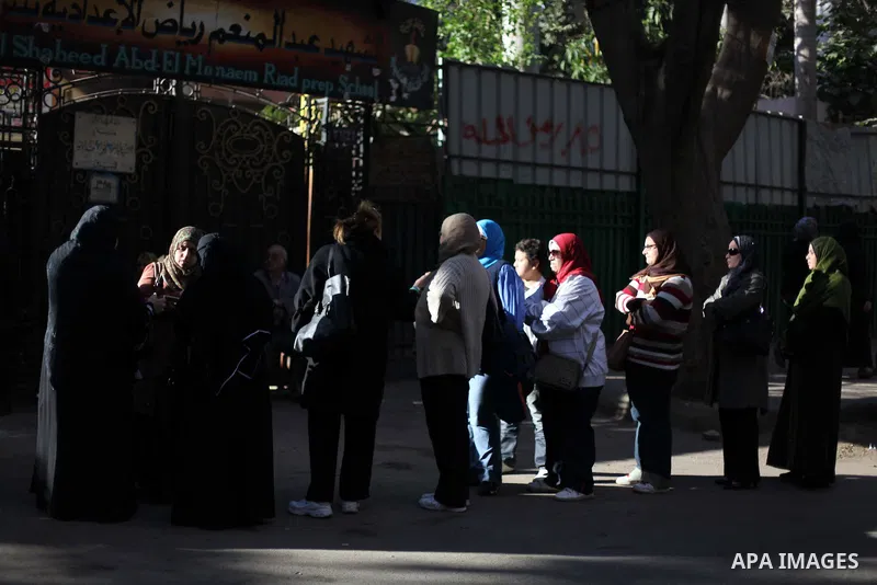 Egyptian women queue with other voters at a polling station during the second round of a referendum on a new draft constitution in Giza, south of Cairo, on December 22, 2012. Egyptians are voting in the final round of a...