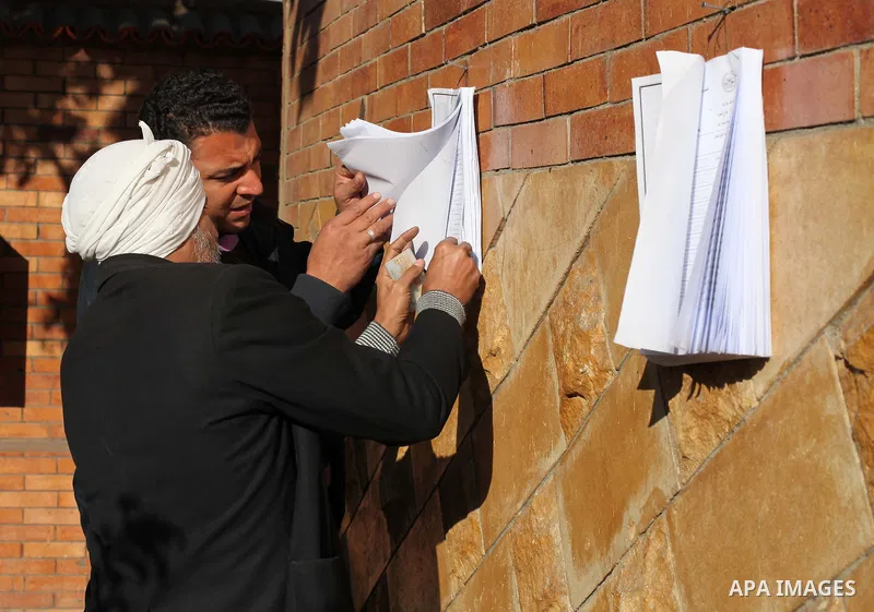 Egyptian men search for their names on the registered voters' list outside a polling station during the second round of a referendum on a new draft constitution in Giza, south of Cairo, on December 22, 2012. Egyptians ar...