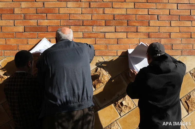 Egyptian men search for their names on the registered voters' list outside a polling station during the second round of a referendum on a new draft constitution in Giza, south of Cairo, on December 22, 2012. Egyptians ar...