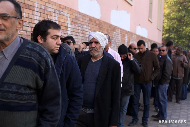 Egyptian men queue with other voters at a polling station during the second round of a referendum on a new draft constitution in Giza, south of Cairo, on December 22, 2012. Egyptians are voting in the final round of a re...