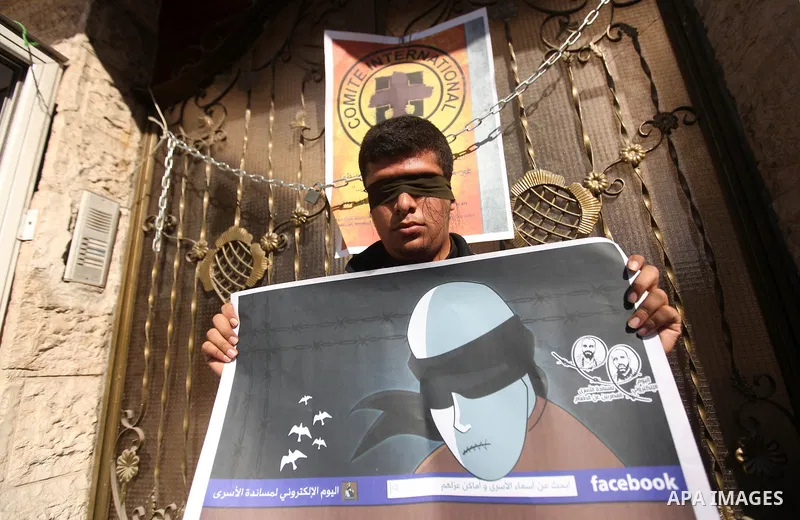 A Palestinian man who covered their eyes with black ribbons demonstrate in support of Palestinian prisoners held in Israeli jails, some of whom are observing a hunger strike, in Gaza City on December 22, 2012. Photo by M...
