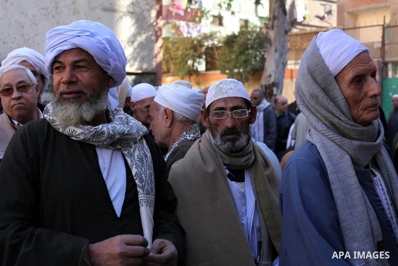 Egyptian men queue with other voters at a polling station during the second round of a referendum on a new draft constitution in Giza, south of Cairo, on December 22, 2012. Egyptians are voting in the final round of a re...