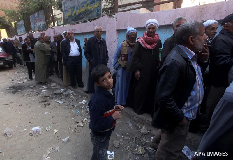 Egyptian men queue with other voters at a polling station during the second round of a referendum on a new draft constitution in Giza, south of Cairo, on December 22, 2012. Egyptians are voting in the final round of a re...