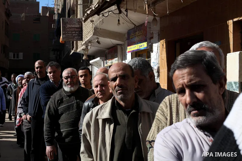 Egyptian men queue with other voters at a polling station during the second round of a referendum on a new draft constitution in Giza, south of Cairo, on December 22, 2012. Egyptians are voting in the final round of a re...