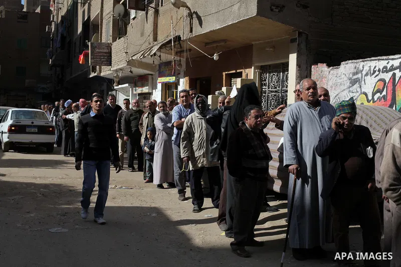Egyptian men queue with other voters at a polling station during the second round of a referendum on a new draft constitution in Giza, south of Cairo, on December 22, 2012. Egyptians are voting in the final round of a re...