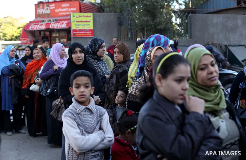 Egyptian women queue with other voters at a polling station during the second round of a referendum on a new draft constitution in Giza, south of Cairo, on December 22, 2012. Egyptians are voting in the final round of a...