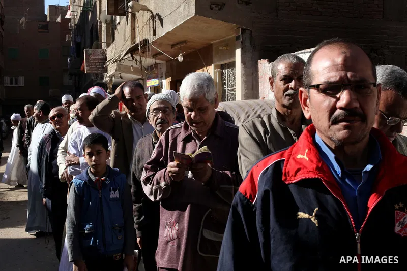 Egyptian men queue with other voters at a polling station during the second round of a referendum on a new draft constitution in Giza, south of Cairo, on December 22, 2012. Egyptians are voting in the final round of a re...