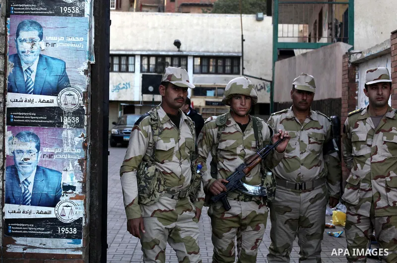 Members of Egyptian army stand guard at the entrance of the polling station, during the second round of a referendum for the new Egyptian constitution, in Giza, south of Cairo, Egypt, 22 December 2012. More than 25 milli...