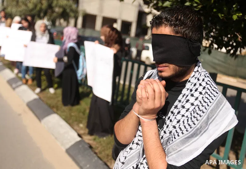 Palestinians youth hold a poster to show his support for Palestinian prisoners currently being held in Israeli jails, some of whom are on hunger strike, in Gaza city, 23, 2012. Photo by Majdi Fathi