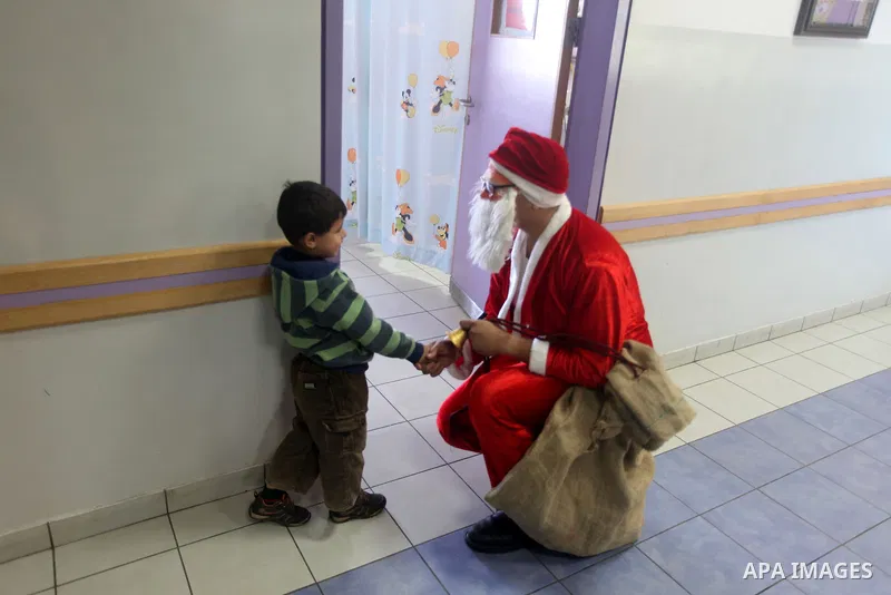 Palestinian Man dressed as Santa Claus give the Children a present in the hospital in the West Bank city of Ramallah on 23 December 2012 .Palestinian Christians across the Israeli occupied Palestinian West Bank are prepa...