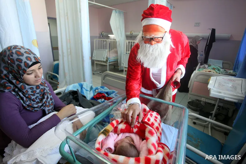 Palestinian Man dressed as Santa Claus give the Children a present in the hospital in the West Bank city of Ramallah on 23 December 2012 .Palestinian Christians across the Israeli occupied Palestinian West Bank are prepa...