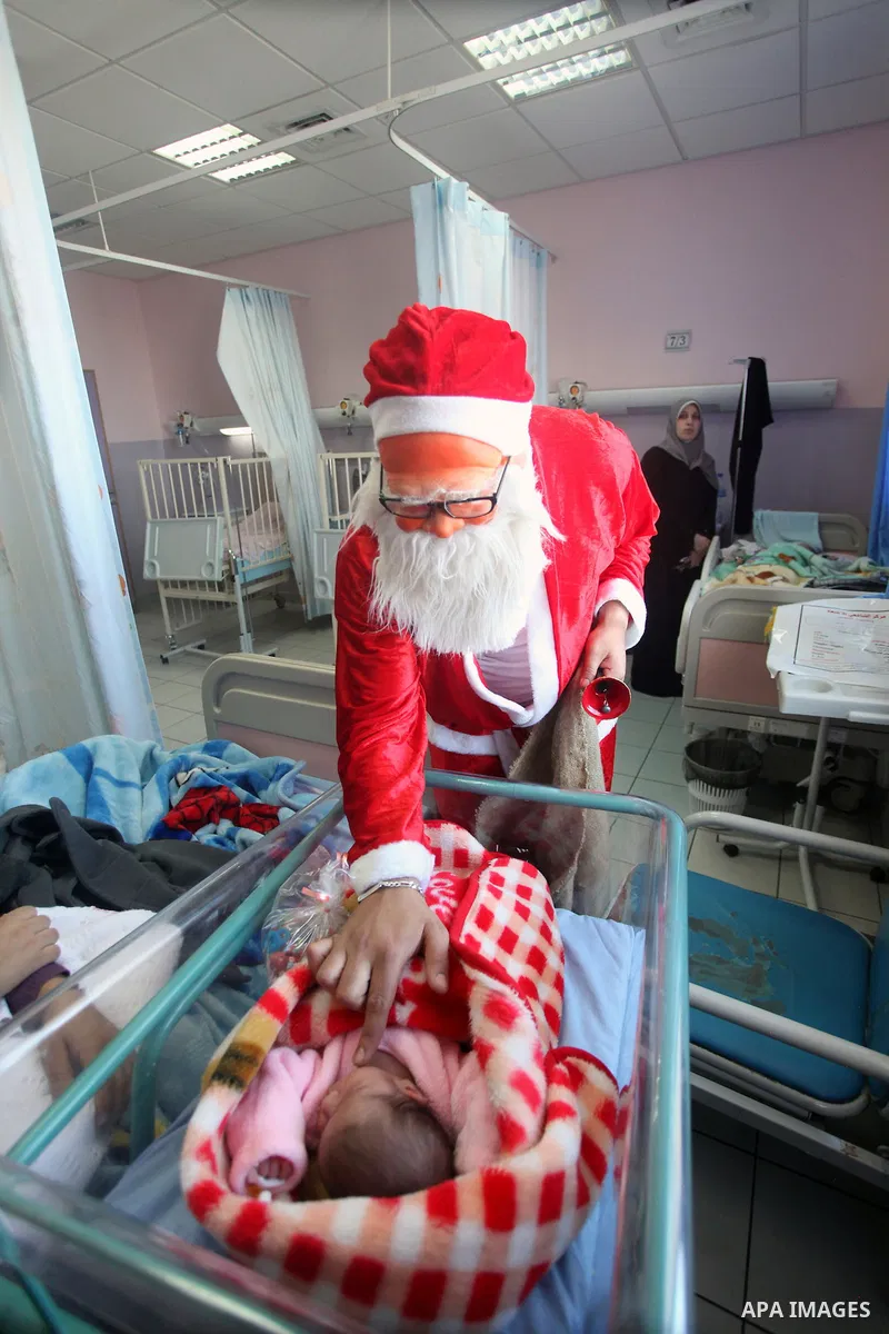 Palestinian Man dressed as Santa Claus give the Children a present in the hospital in the West Bank city of Ramallah on 23 December 2012 .Palestinian Christians across the Israeli occupied Palestinian West Bank are prepa...