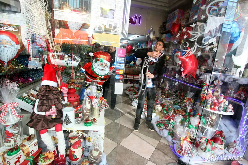 Palestinian vendor decorates his store for the upcoming Christmas festivities in the West Bank city of Ramallah on 23 December 2012 .Christmas is celebrated Christians across the globe on December 25 every year. Photo by...
