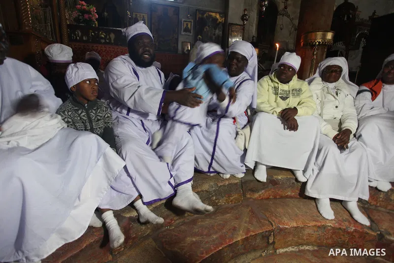 Nigerian pilgrims sit inside the 'Grotto,' where Christians believe the Virgin Mary gave birth to Jesus Christ, in the Church of the Nativity, in the West Bank town of Bethlehem on Christmas Day, 24 December 2012. Photo...