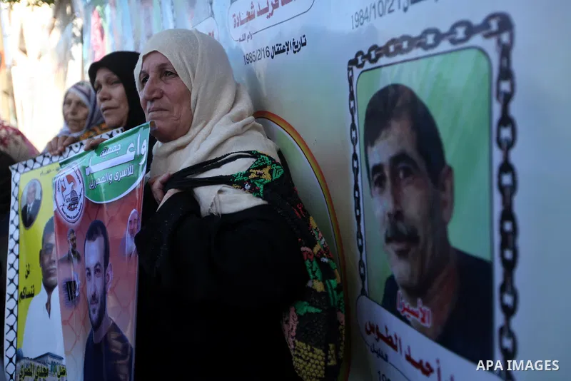 Palestinians hold pictures of prisoners held in the Israeli jails during a rally in Gaza city on December 24, 2012. in solidarity with hunger-striking detainees held by Israel to demand their release from detention witho...