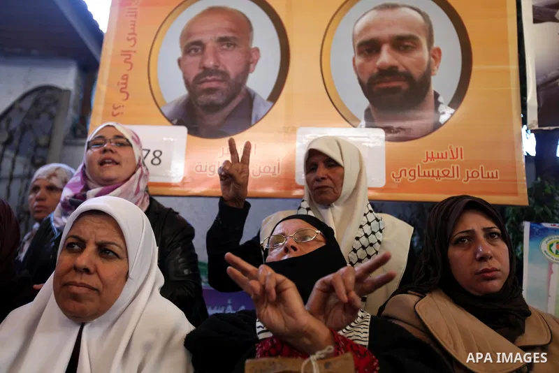 Palestinians hold pictures of prisoners held in the Israeli jails during a rally in Gaza city on December 24, 2012. in solidarity with hunger-striking detainees held by Israel to demand their release from detention witho...