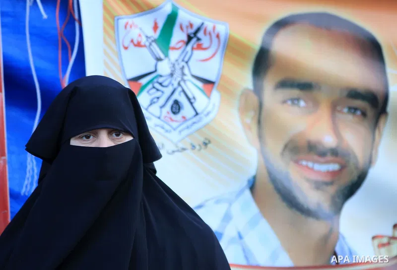 Palestinians hold pictures of prisoners held in the Israeli jails during a rally in Gaza city on December 24, 2012. in solidarity with hunger-striking detainees held by Israel to demand their release from detention witho...