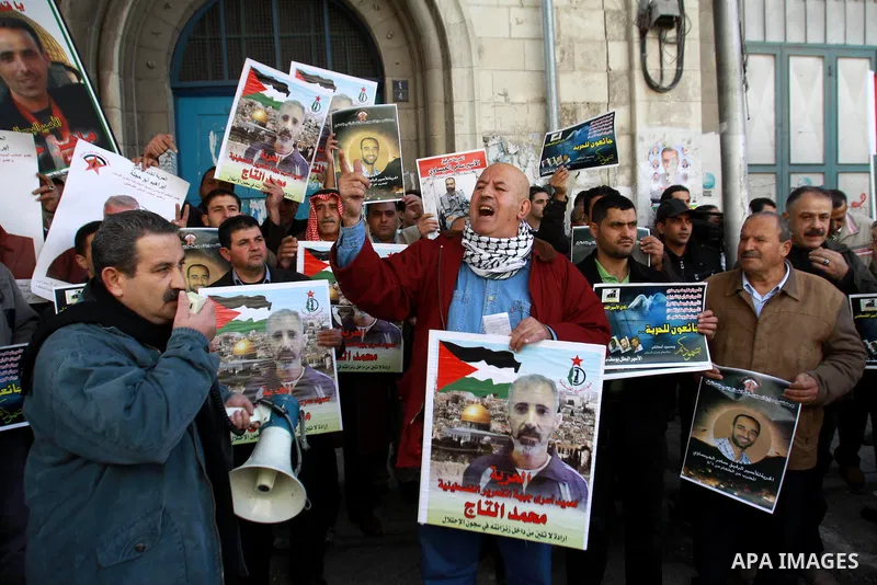 Palestinians hold pictures of prisoners held in the Israeli jails during a rally in front of UN offices in the West Bank city of Nablus on December 24, 2012. in solidarity with hunger-striking detainees held by Israel to...
