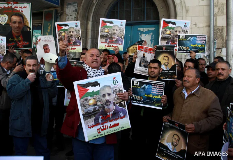 Palestinians hold pictures of prisoners held in the Israeli jails during a rally in front of UN offices in the West Bank city of Nablus on December 24, 2012. in solidarity with hunger-striking detainees held by Israel to...