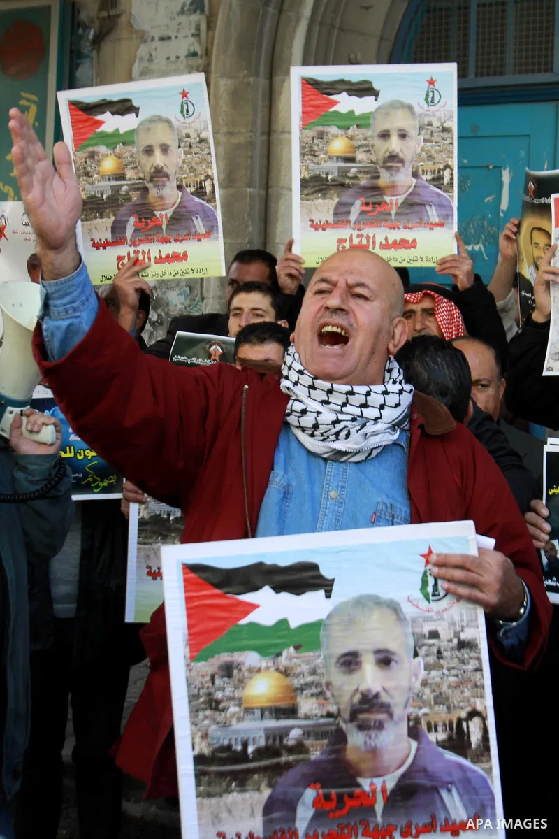 Palestinians hold pictures of prisoners held in the Israeli jails during a rally in front of UN offices in the West Bank city of Nablus on December 24, 2012. in solidarity with hunger-striking detainees held by Israel to...