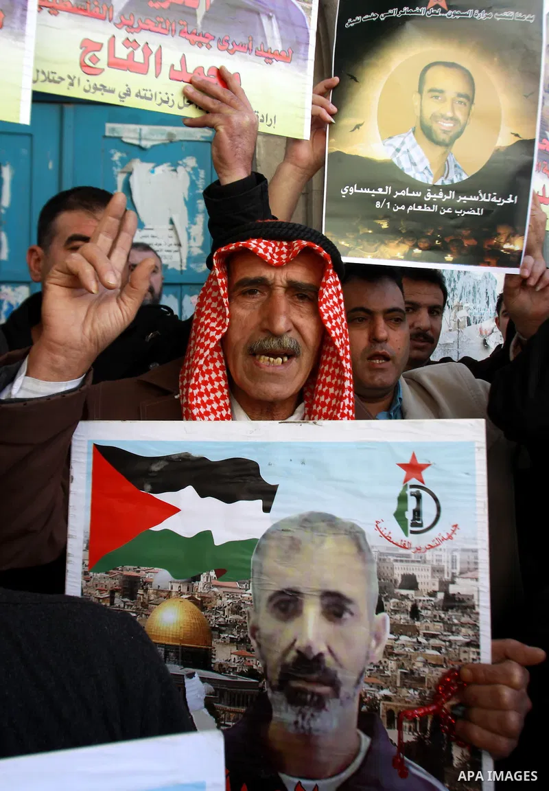 Palestinians hold pictures of prisoners held in the Israeli jails during a rally in front of UN offices in the West Bank city of Nablus on December 24, 2012. in solidarity with hunger-striking detainees held by Israel to...
