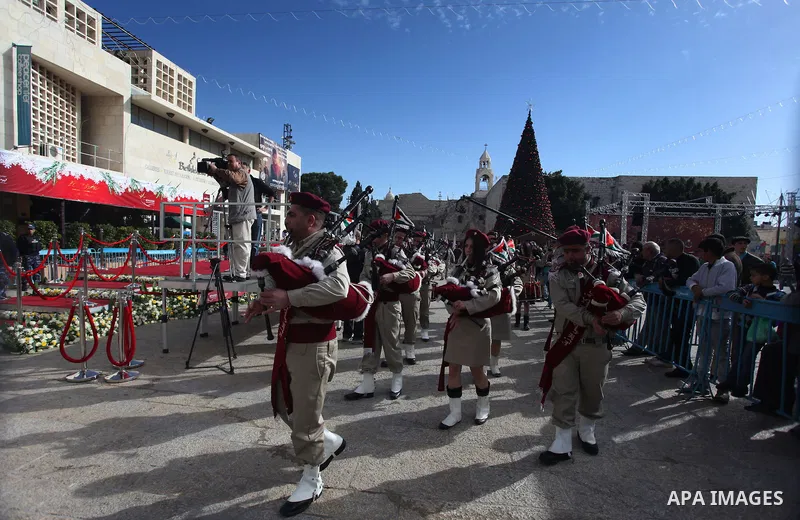 Palestinians celebrate around a Christmas tree at the Manger Square, outside the Church of the Nativity, in the West Bank town of Bethlehem, Sunday, Dec. 24, 2012. Thousands of Palestinians and tourists were flocking to...