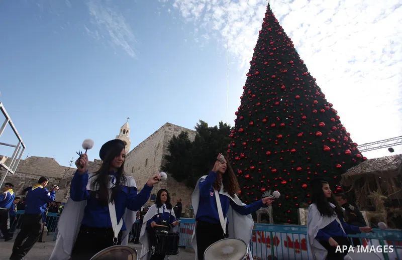 Palestinians celebrate around a Christmas tree at the Manger Square, outside the Church of the Nativity, in the West Bank town of Bethlehem, Sunday, Dec. 24, 2012. Thousands of Palestinians and tourists were flocking to...