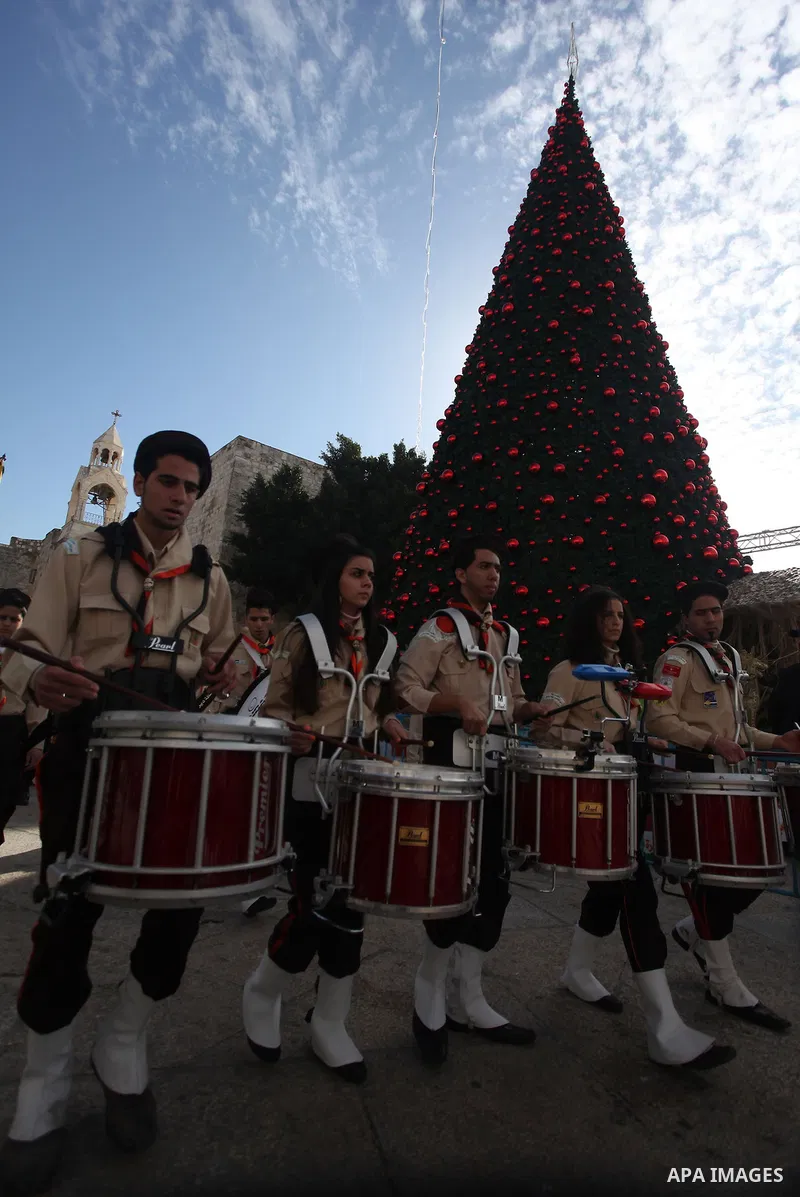 Palestinians celebrate around a Christmas tree at the Manger Square, outside the Church of the Nativity, in the West Bank town of Bethlehem, Sunday, Dec. 24, 2012. Thousands of Palestinians and tourists were flocking to...