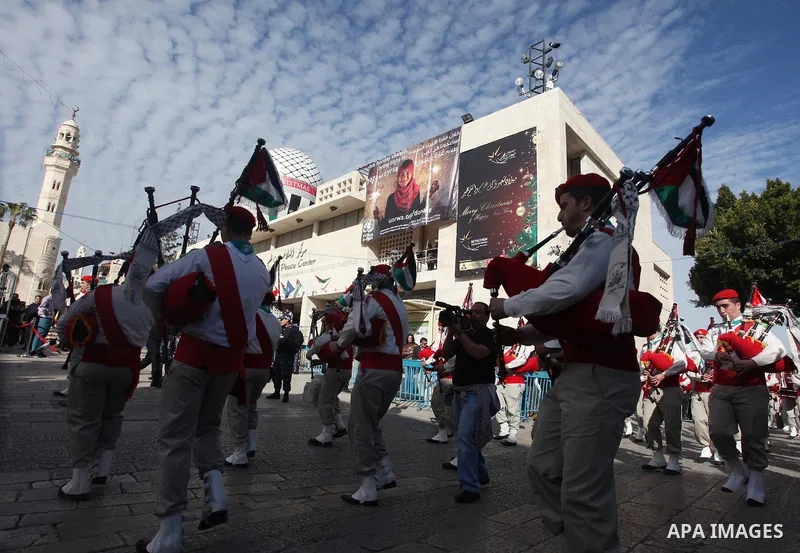 Palestinians celebrate around a Christmas tree at the Manger Square, outside the Church of the Nativity, in the West Bank town of Bethlehem, Sunday, Dec. 24, 2012. Thousands of Palestinians and tourists were flocking to...