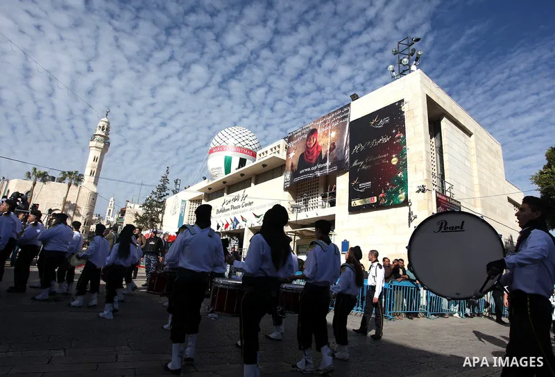 Palestinians celebrate around a Christmas tree at the Manger Square, outside the Church of the Nativity, in the West Bank town of Bethlehem, Sunday, Dec. 24, 2012. Thousands of Palestinians and tourists were flocking to...