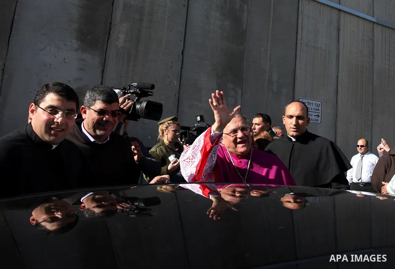 The Latin Patriarch of Jerusalem Fuad Twal, the head of the Roman Catholic Church in the Holy Land, waves to the crowds as he arrives in the West Bank city of Bethlehem after crossing Israel's separation barrier on Decem...