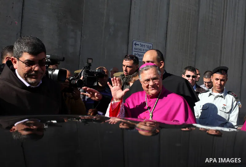 The Latin Patriarch of Jerusalem Fuad Twal, the head of the Roman Catholic Church in the Holy Land, waves to the crowds as he arrives in the West Bank city of Bethlehem after crossing Israel's separation barrier on Decem...