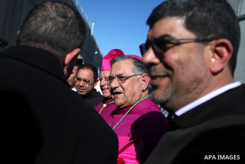 The Latin Patriarch of Jerusalem Fuad Twal, the head of the Roman Catholic Church in the Holy Land, talks to officials as he arrives in the West Bank city of Bethlehem after crossing Israel's separation barrier on Decemb...
