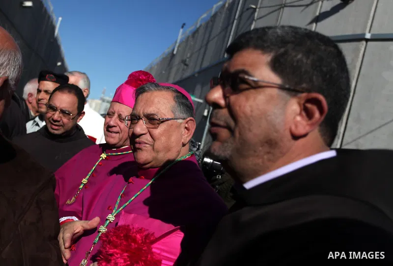 The Latin Patriarch of Jerusalem Fuad Twal, the head of the Roman Catholic Church in the Holy Land, talks to officials as he arrives in the West Bank city of Bethlehem after crossing Israel's separation barrier on Decemb...